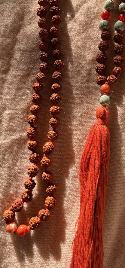 Japamala de rudraksha de 9mm en color rojizo. Borla en naranja, agata roja más cuentas de cristal de murano turquesas